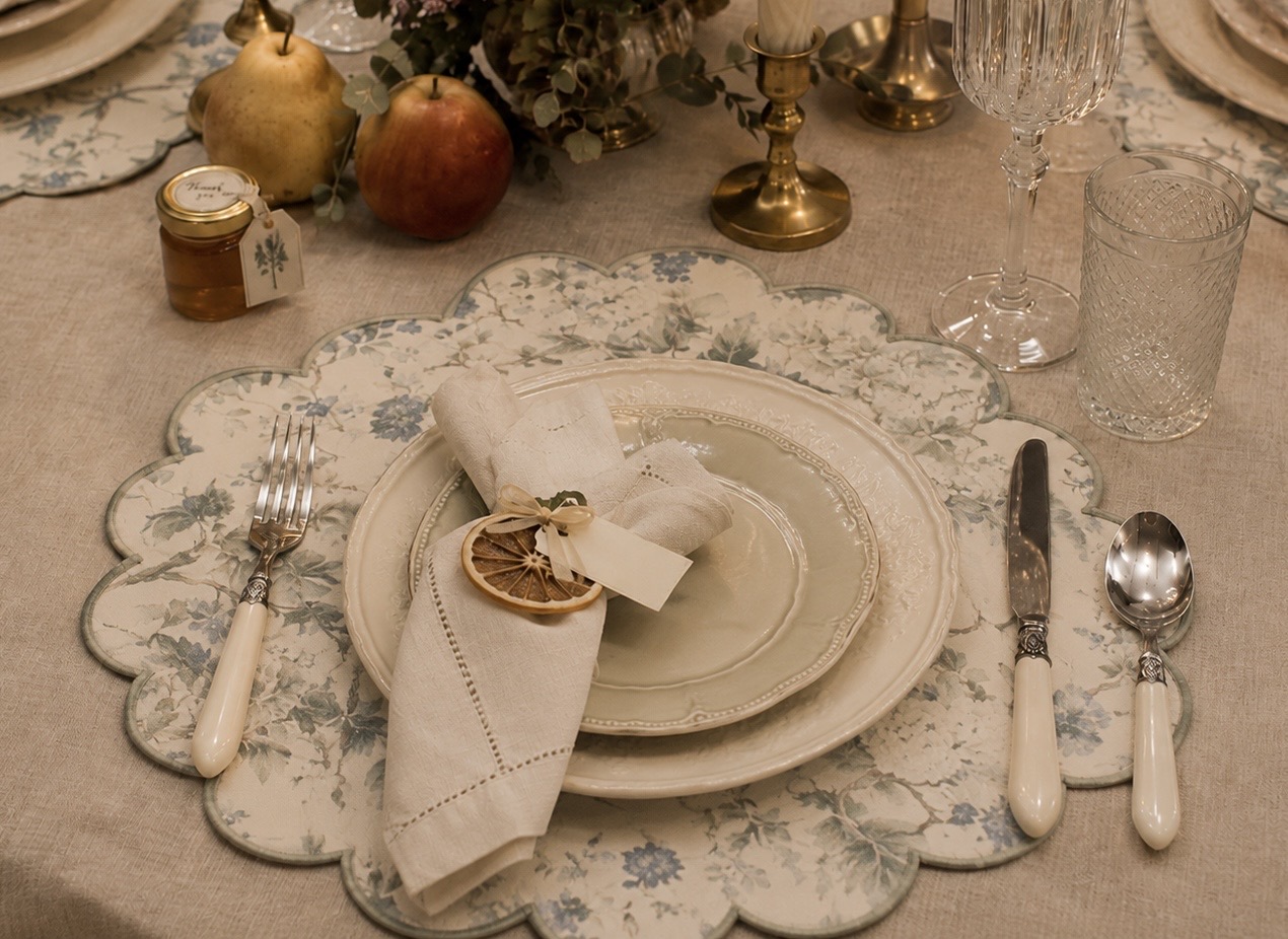Scalloped floral fabric placemat set with cream china, linen napkin and dried orange slice